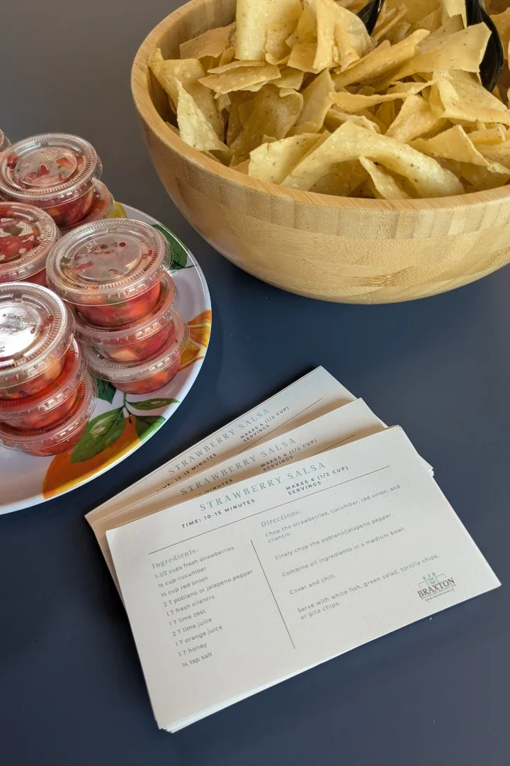 Take-home recipe cards fanned out on a table with chips and salsa from a workplace wellness session